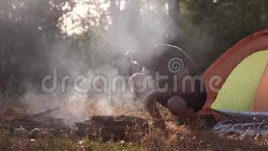 一个年轻人正在森林里的火上烤肉。
